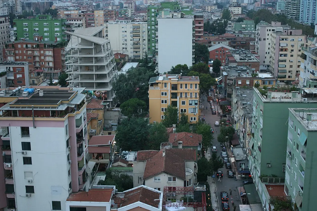 Tirana at dusk, apartment blocks and streets lit up under a fading sky