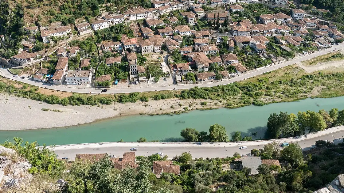 The white Ottoman houses of Berat climbing the hillside above the turquoise Osum river, seen from the castle