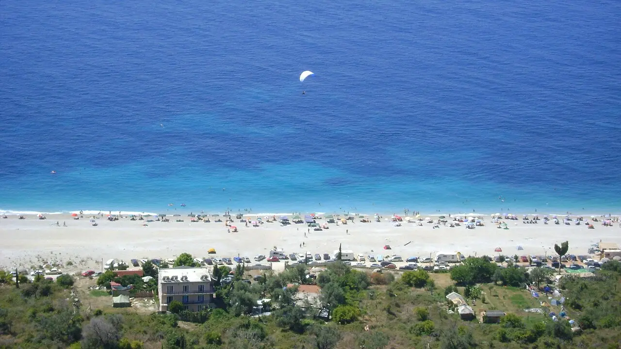 A wide panorama of Dhermi beach on the Albanian Riviera, turquoise water along a long pebble shore below the mountains