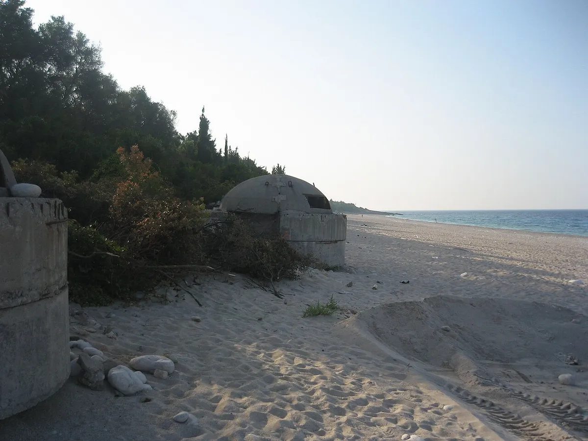 Drymades beach near Dhermi with old concrete bunkers half-buried in the sand and pine trees