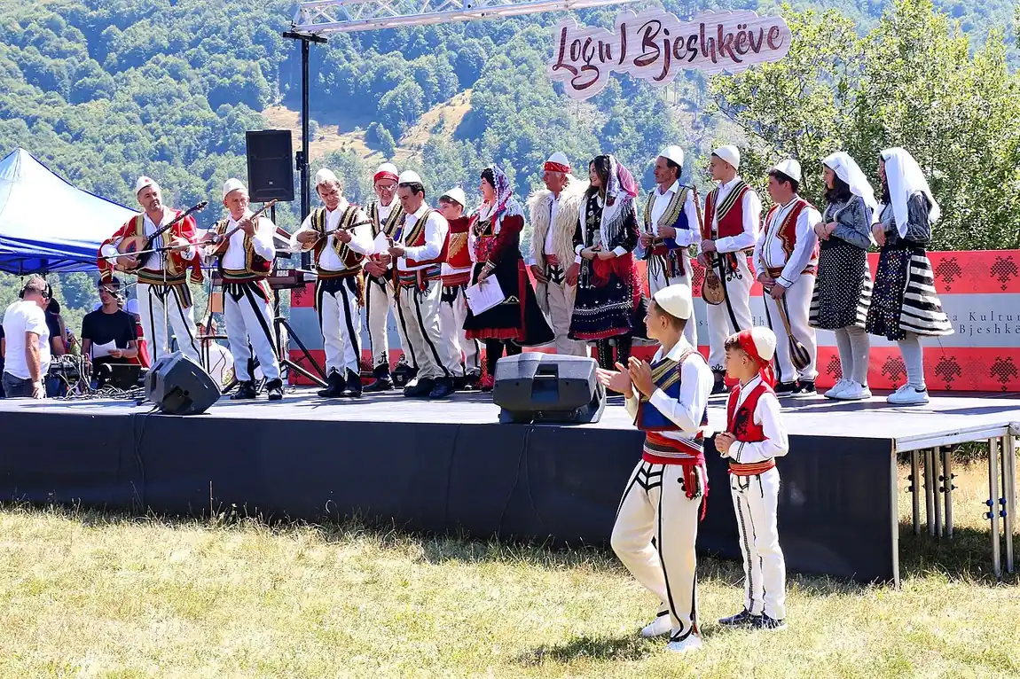 Musicians in white felt caps playing çifteli on the Logu i Bjeshkëve festival stage in the Albanian Alps