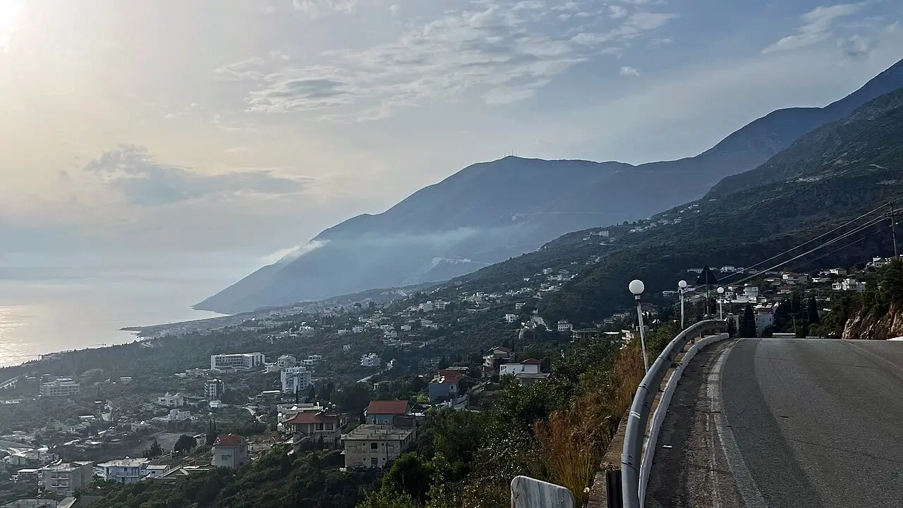 The coast road descending toward Dhermi on the Albanian Riviera, the village and sea below the mountains