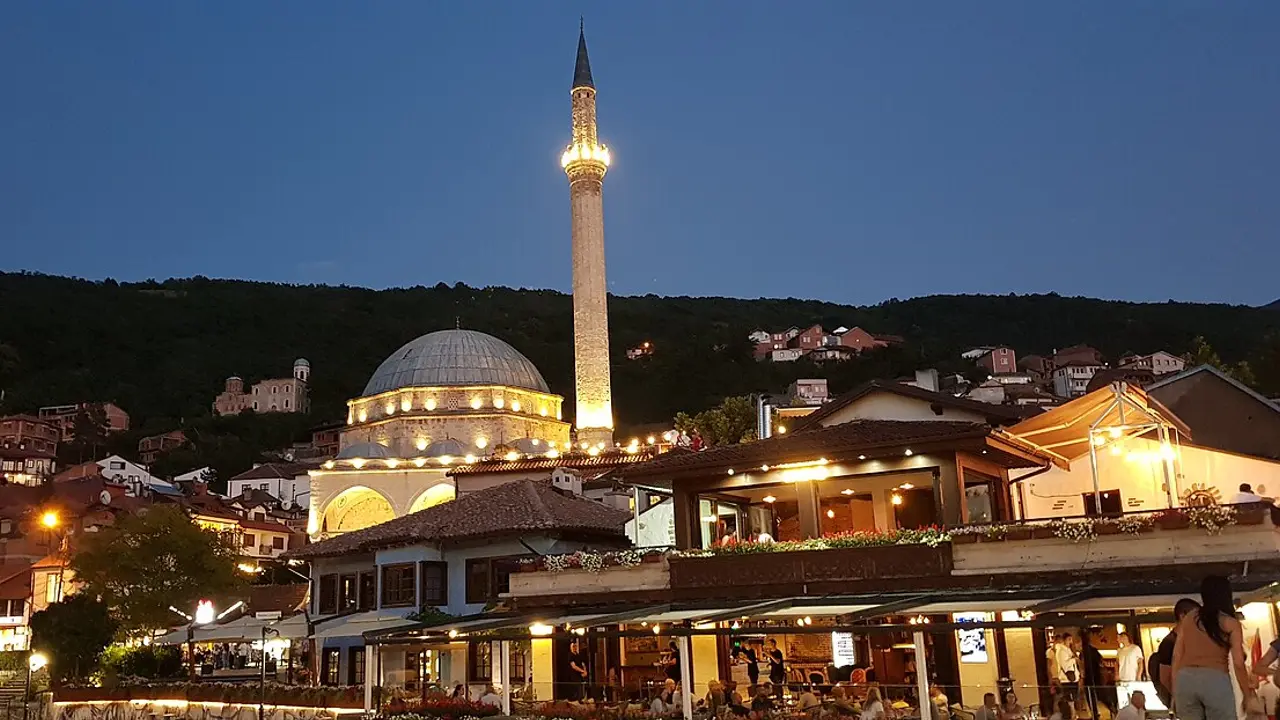 Sinan Pasha Mosque lit up at night, seen across Prizren's old town from the Old Stone Bridge