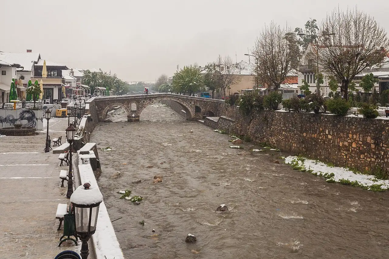 Prizren's old stone bridge over the Lumbardhi river with the town and hills behind