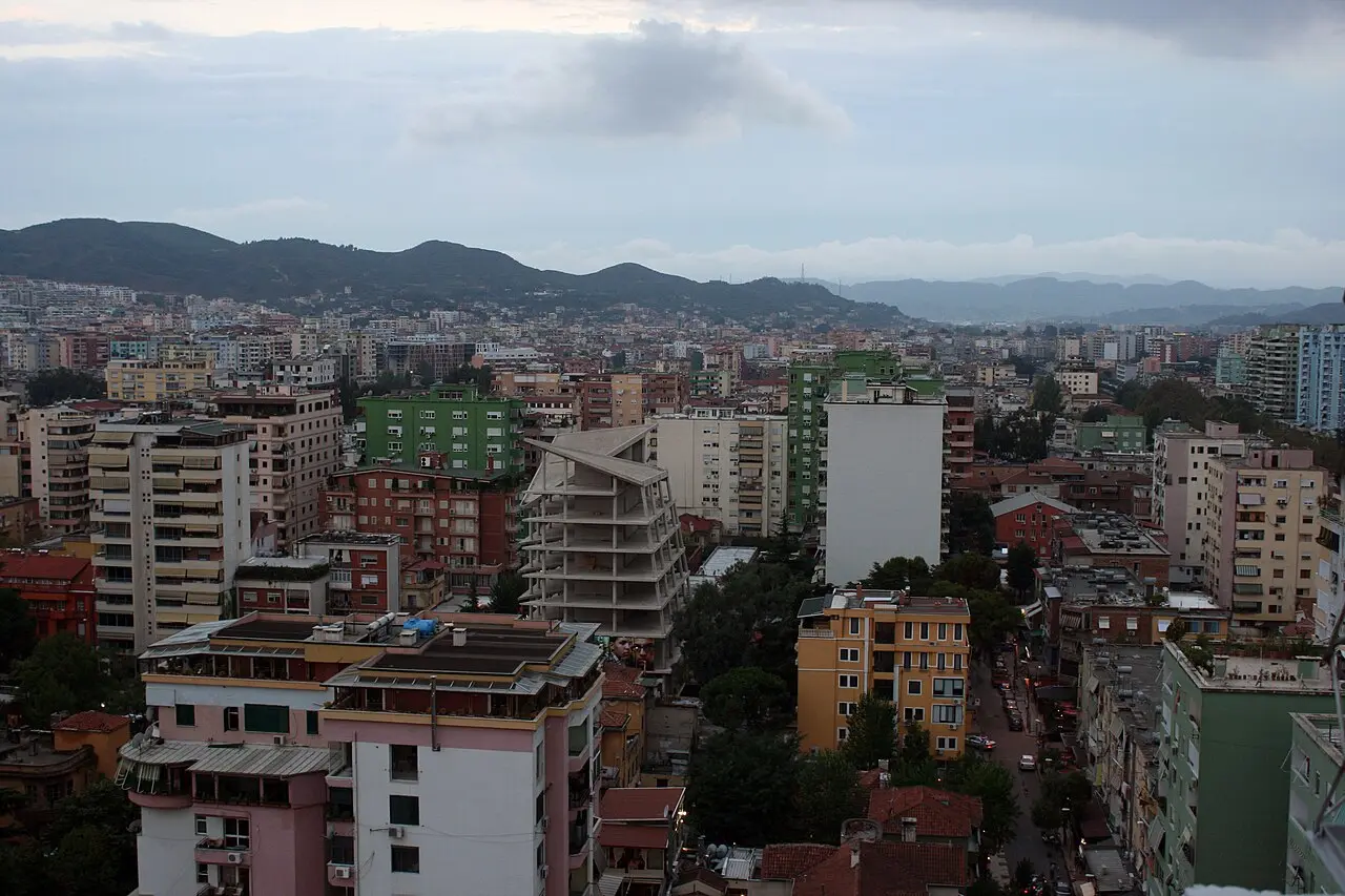 Tirana at dusk, seen across the rooftops toward the hills on the edge of the city