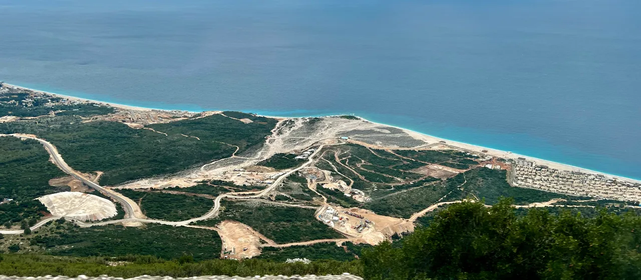 Palasa and Nazar beaches on the Albanian Riviera seen from the descent off the Llogara Pass, with the road dropping to the Ionian Sea