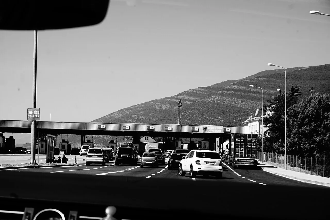 A road border crossing between Kosovo and Albania, with the checkpoint canopy over the lanes