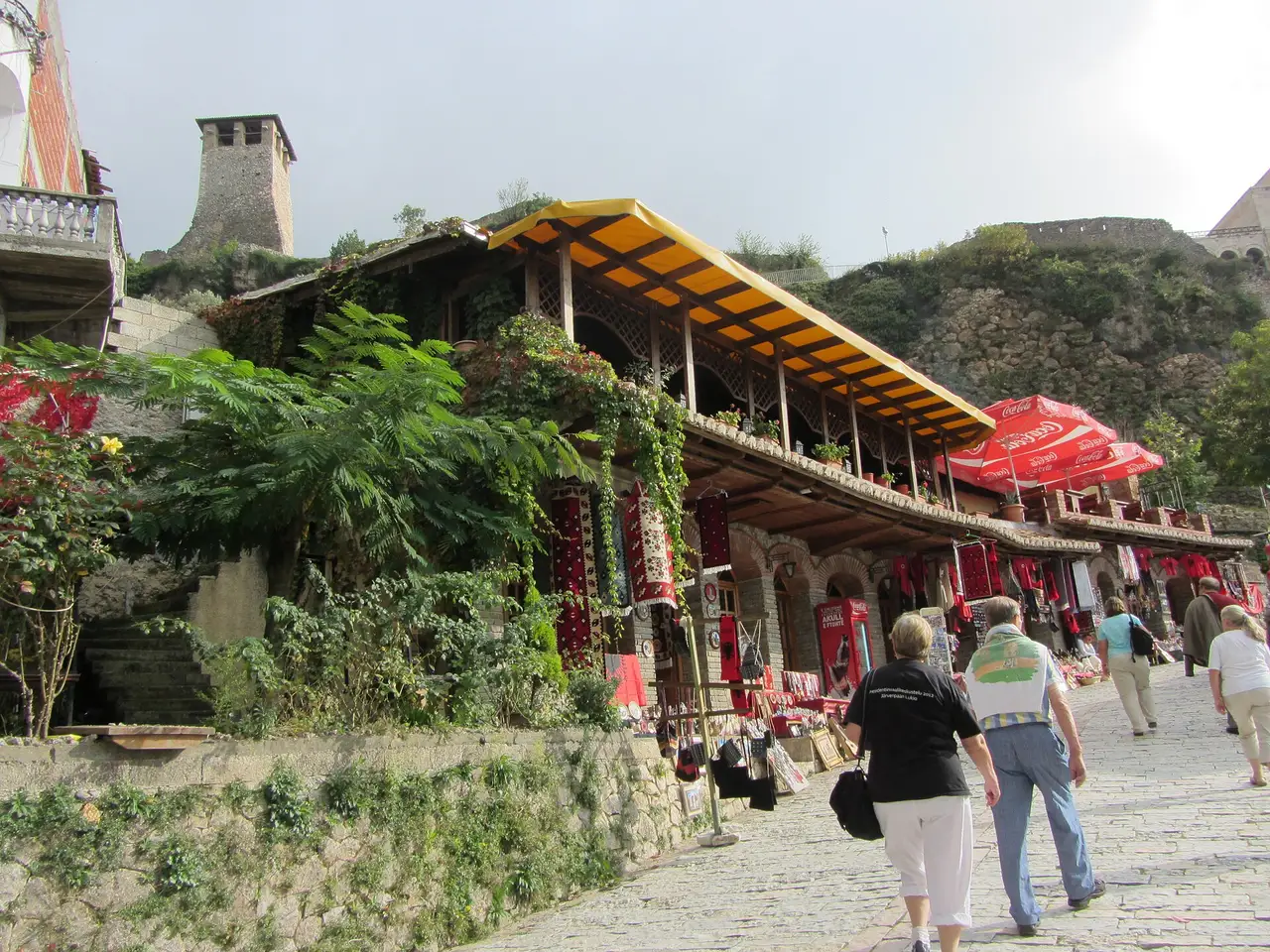 Visitors walking up the cobbled bazaar street in Kruje past stalls hung with carpets and souvenirs