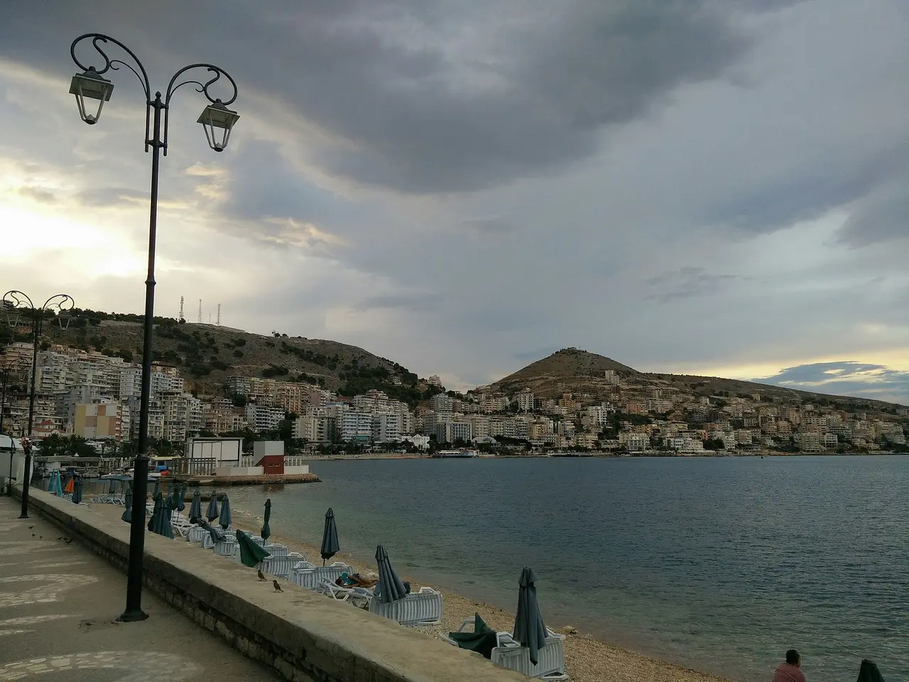 The Saranda seafront early in the morning with folded sun umbrellas, the bay and the town on the hillside