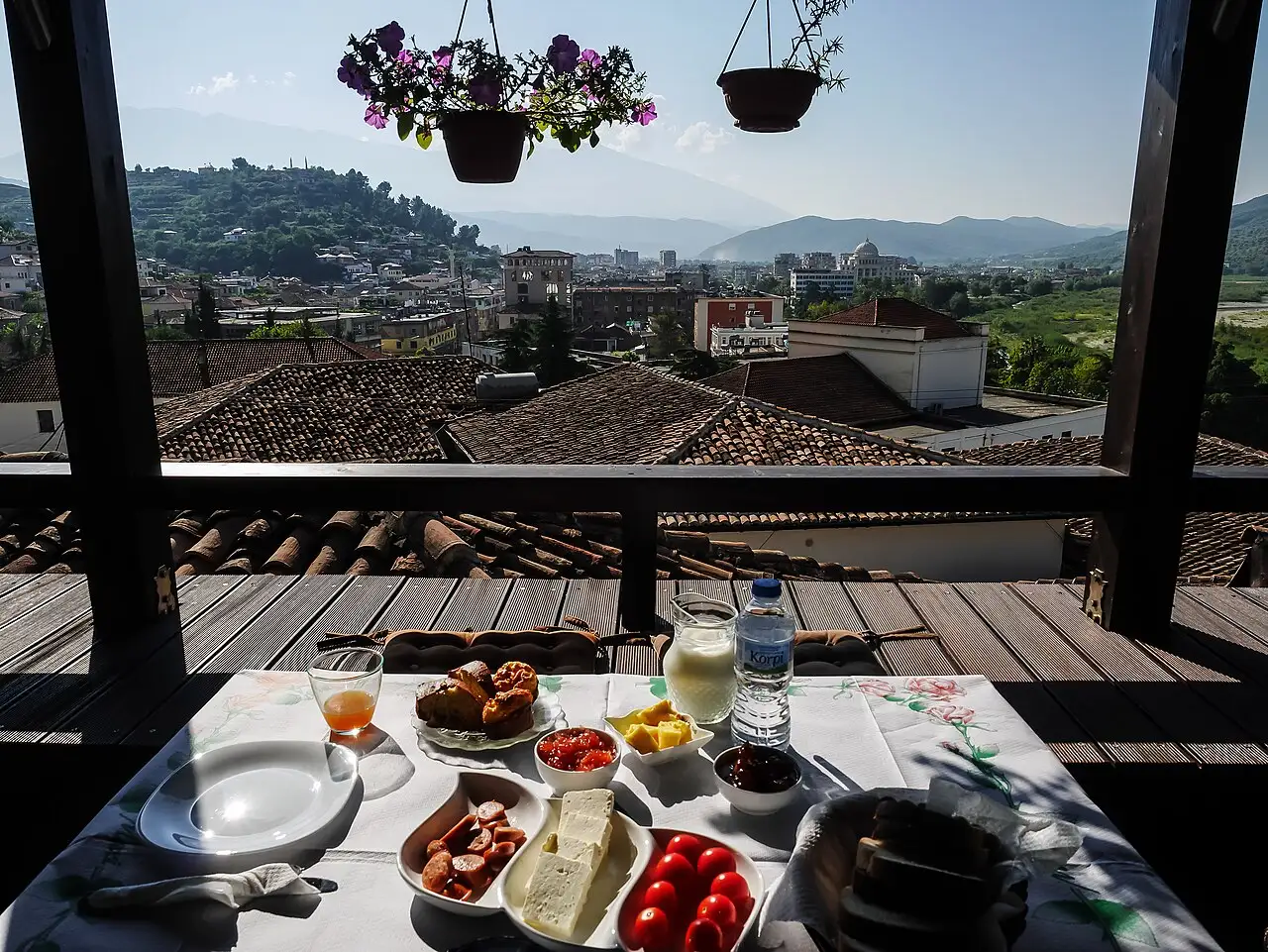 A guesthouse breakfast of feta, tomatoes, sausage, jam and pastries on a terrace overlooking the rooftops of Berat