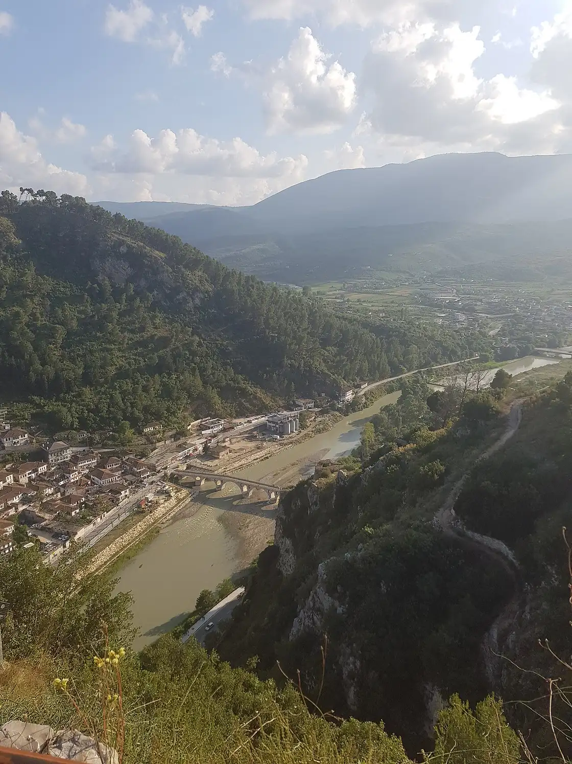 Stone bridge over the Osum river in Berat with mountains behind