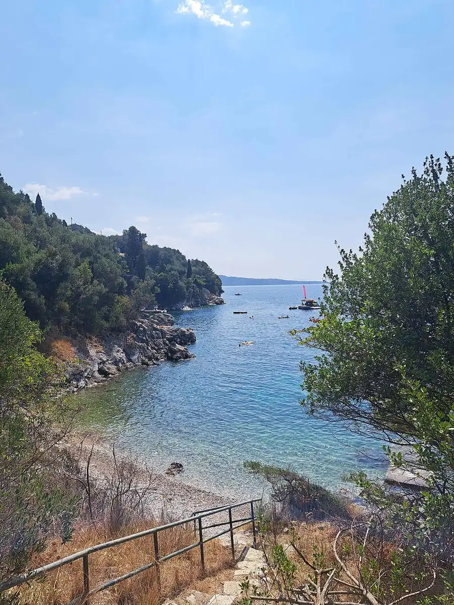 The beach and clear water at Kalami on Corfu, Greece, with green hills behind