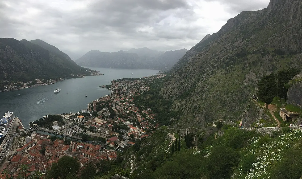 The walled town of Kotor at the foot of steep mountains on the Bay of Kotor in Montenegro, with the fortress climbing the slope above the port