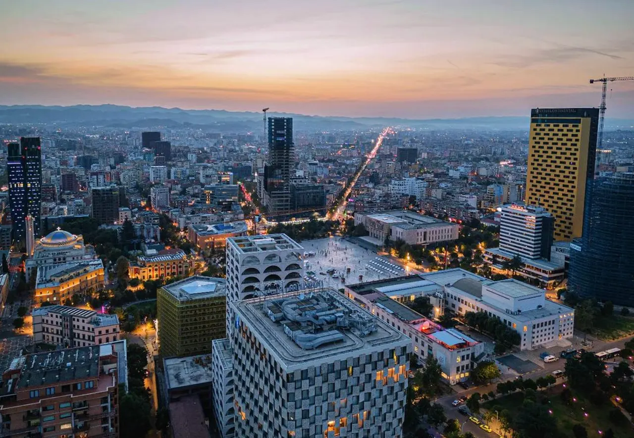 Central Tirana from above at dusk, with the pale open plaza of Skanderbeg Square in the middle of the frame