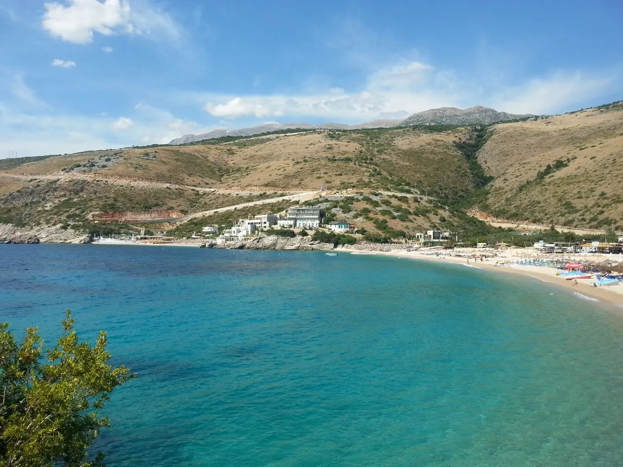 Another angle on Jale bay with clear turquoise water, a crescent beach and loungers along the shore