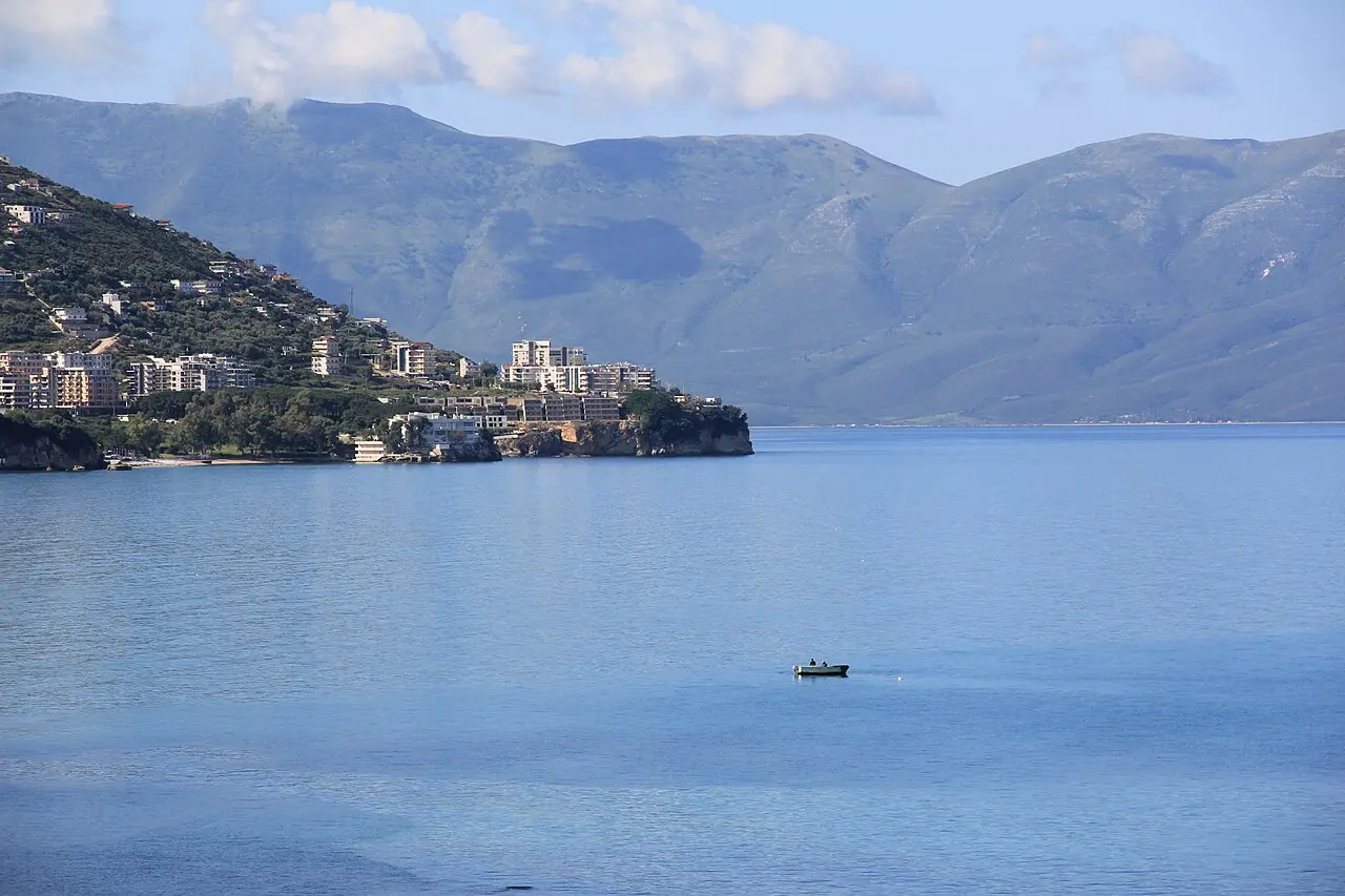 The bay at Vlora with the town on the hillside and the mountains behind, seen across calm water