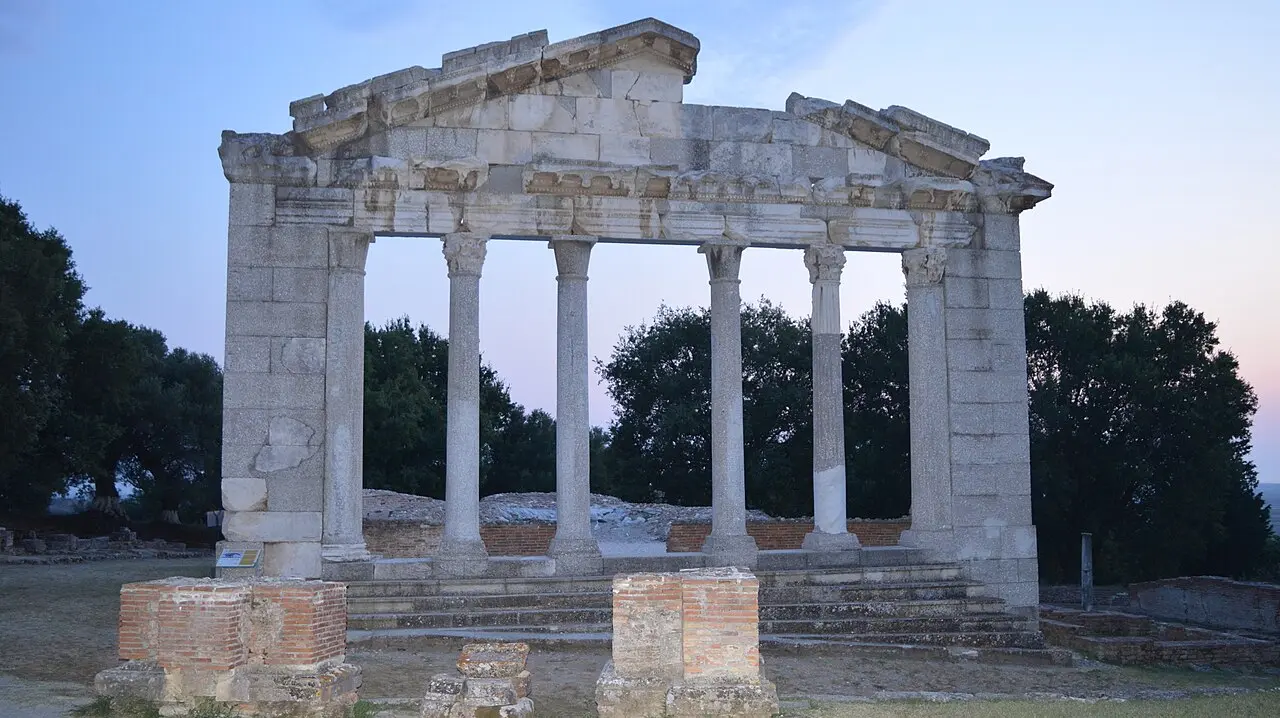 The re-erected six-column facade of the Monument of Agonothetes at Apollonia against a pink dusk sky