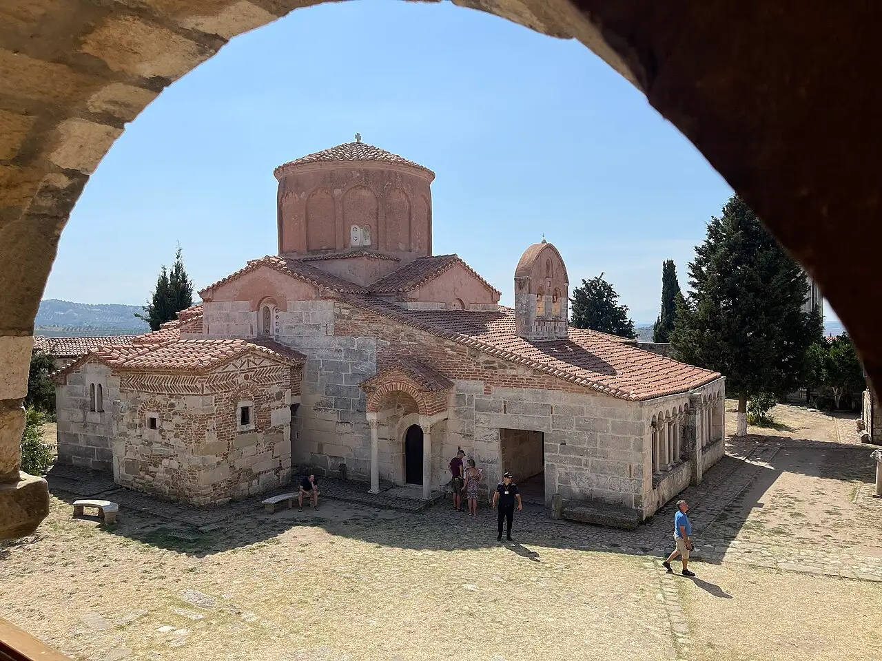 The red-domed Byzantine church and stone cloister of the Monastery of St Mary at Apollonia, seen through an arch