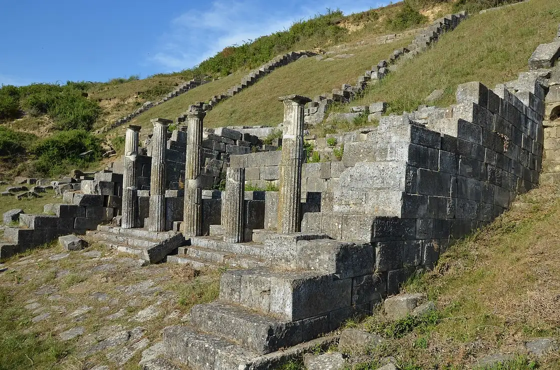 Stepped stone ruins and two column stumps of the nymphaeum at Apollonia on a grassy hillside