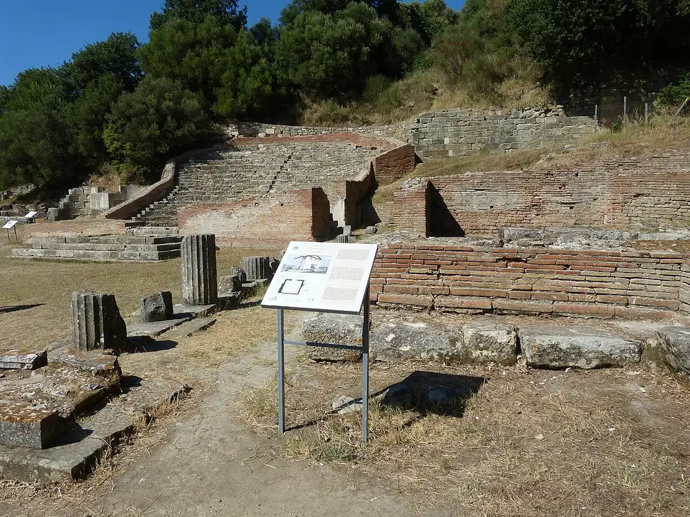 The curved brick seating of the small odeon at Apollonia set into a grassy hillside with an information board