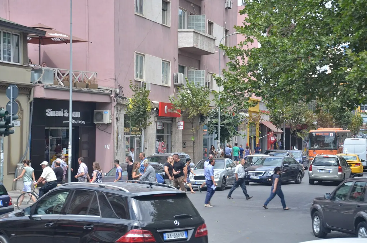 A tree-lined boulevard with traffic and buildings in Tirana