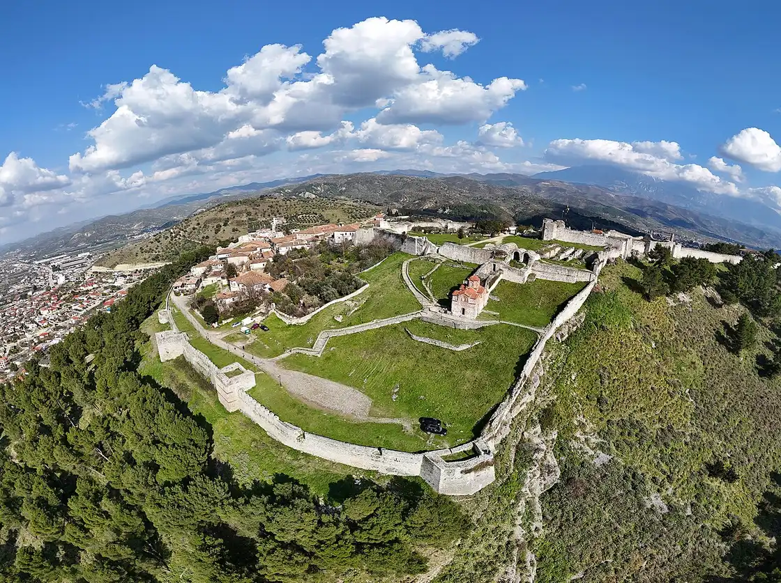 Aerial view of Berat Castle on its hilltop ridge surrounded by walls with the valley beyond