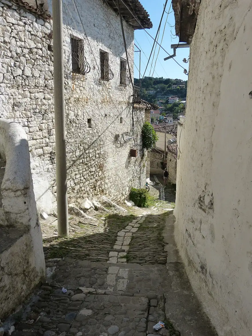 A narrow cobbled lane between stone houses climbing the hillside in the Mangalem quarter of Berat
