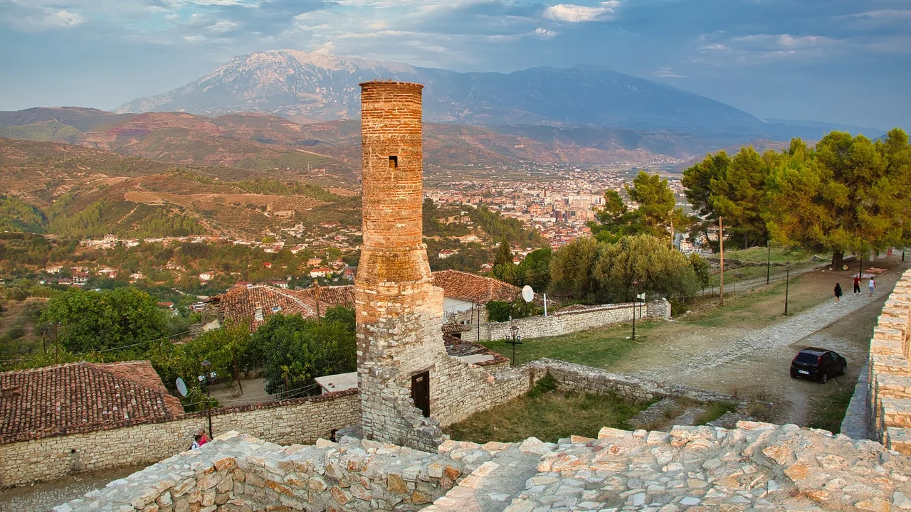 The brick minaret of a ruined mosque inside Berat Castle, with the town in the valley and Mount Tomorr behind