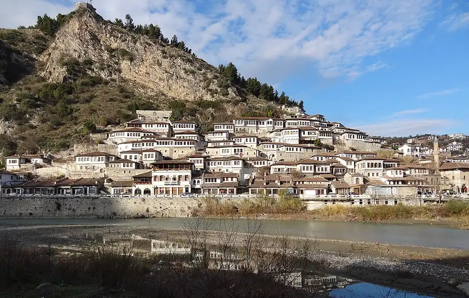 White Ottoman houses of the Mangalem quarter climbing the hillside in Berat with green slopes behind