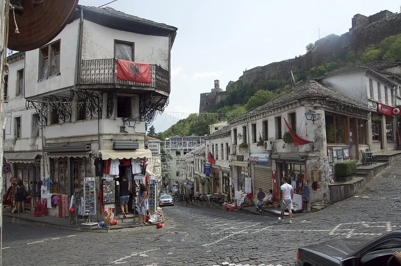The cobbled bazaar street of Gjirokaster, stone-slab roofs on the right and the castle on the ridge above