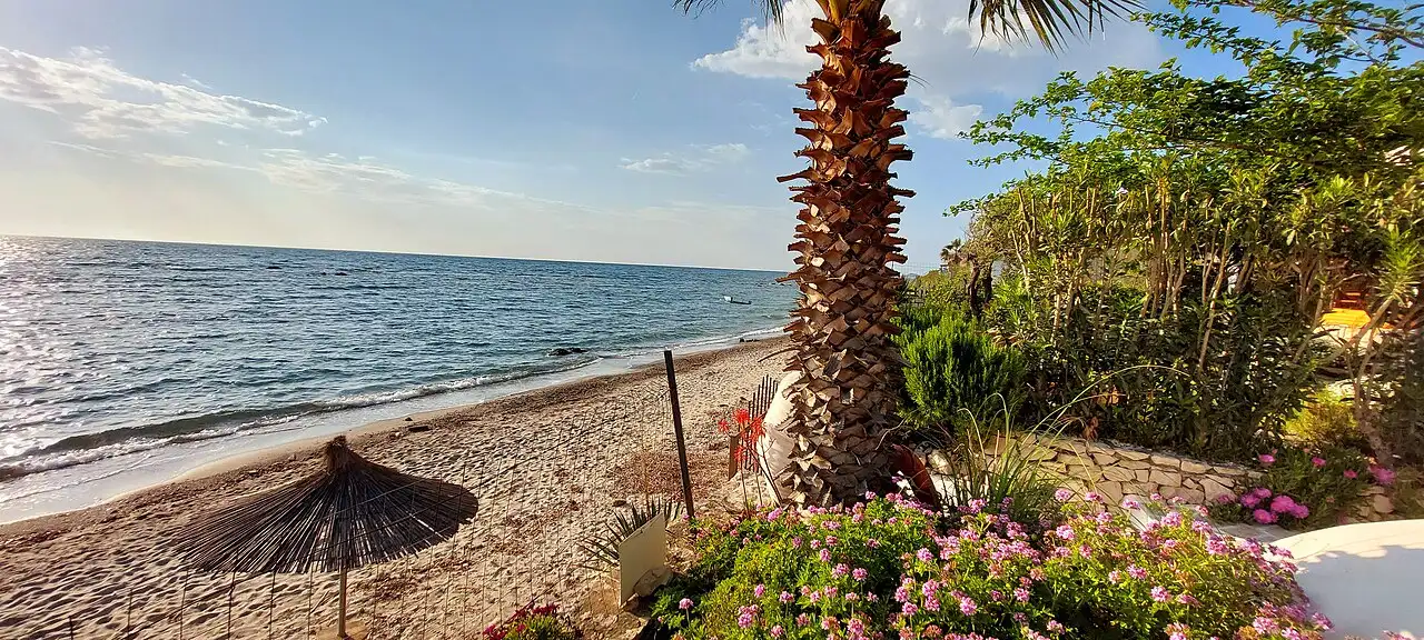 The wide flat sand of Kallm beach north of Durres with calm shallow Adriatic water and few people