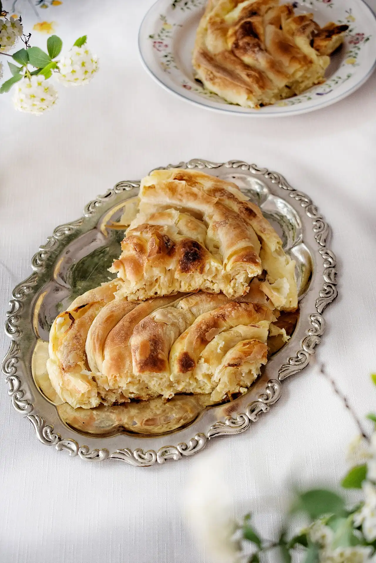 A slice of Albanian cheese byrek, flaky layered pastry, on a plate