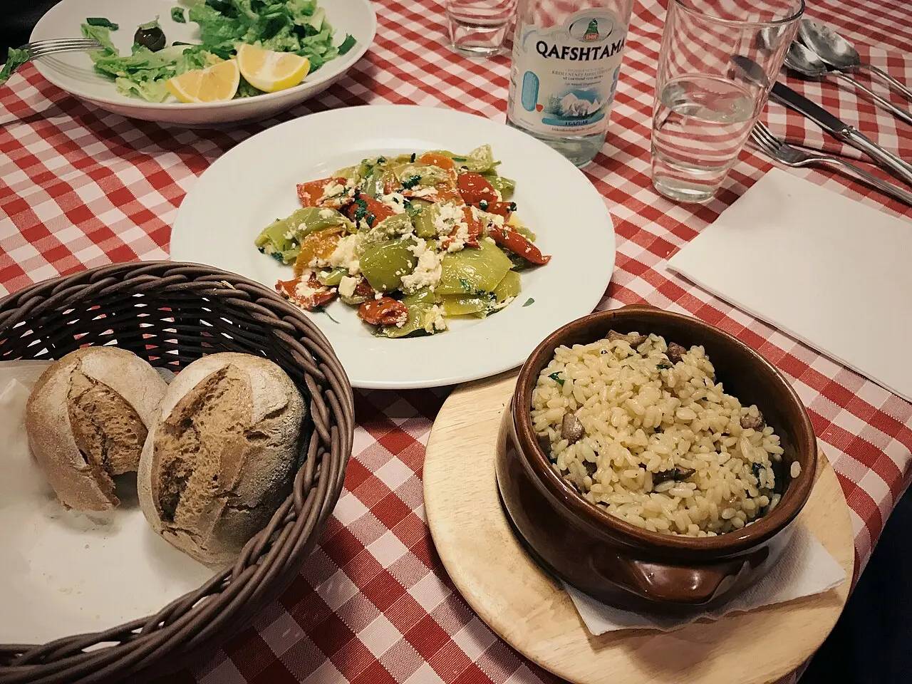 A clay dish of fërgesë with a side of tavë me oriz, baked rice, on a restaurant table in Tirana