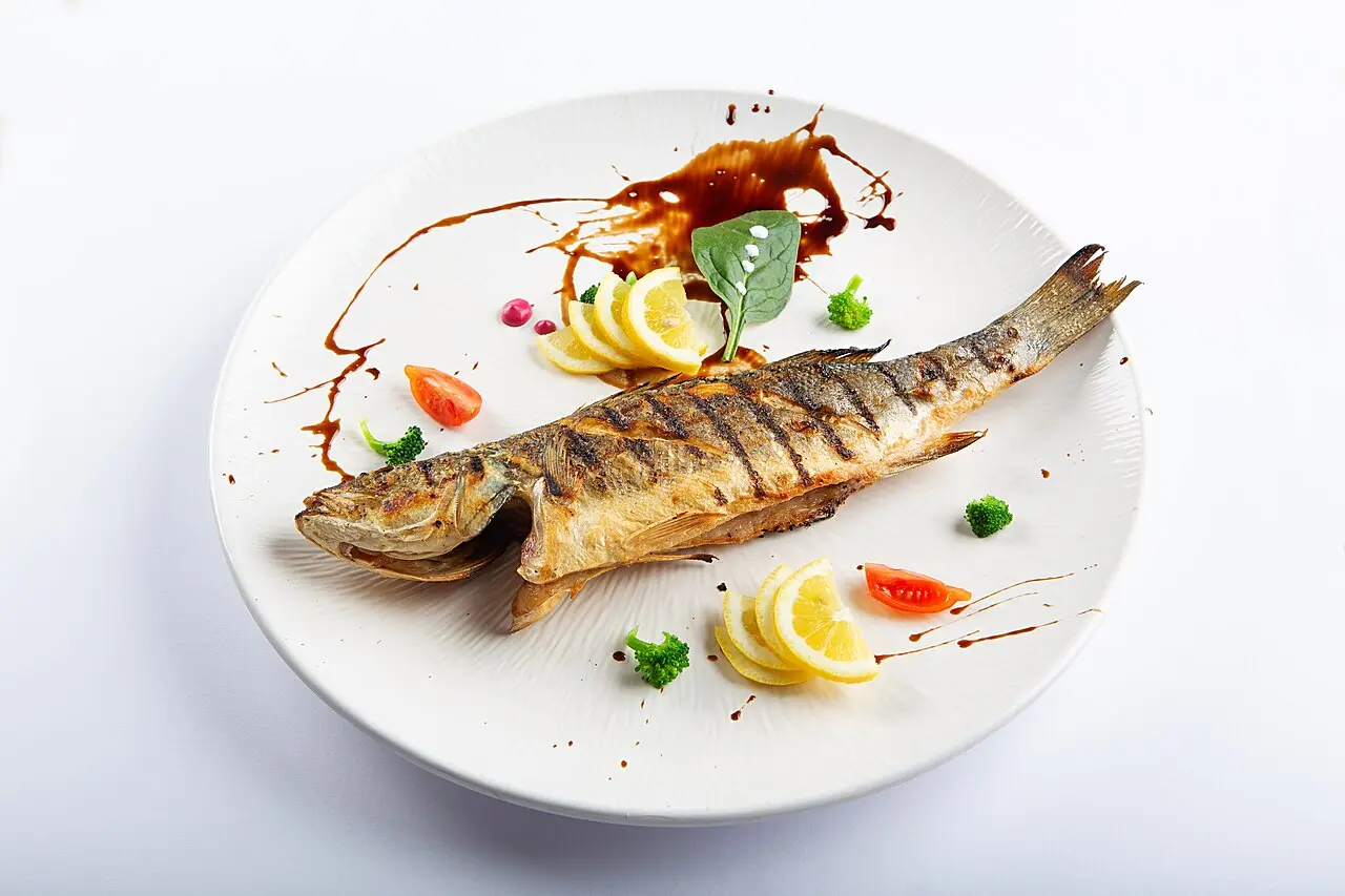 A whole grilled fish on a plate, the kind served at seafood restaurants in Tirana