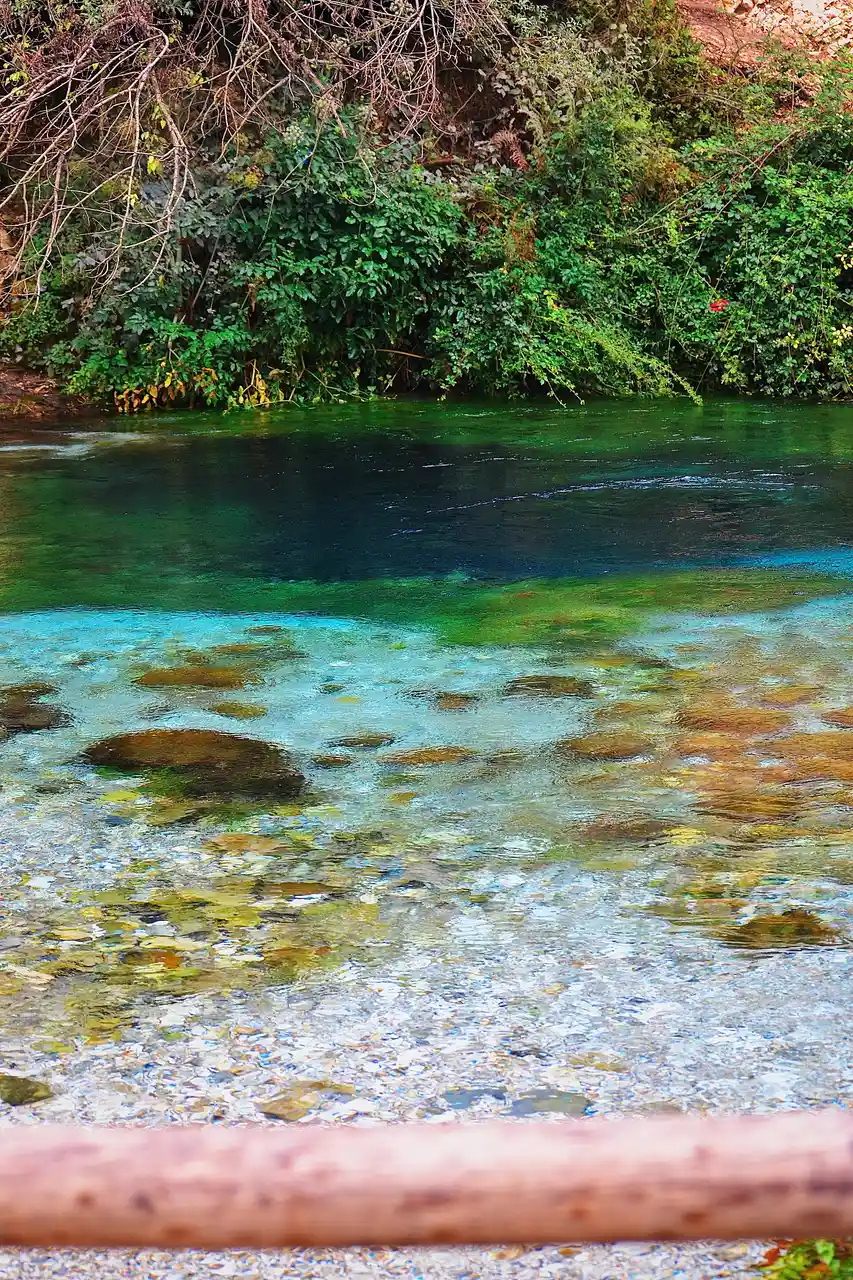 Turquoise water swirling out from the Blue Eye spring over pale rock