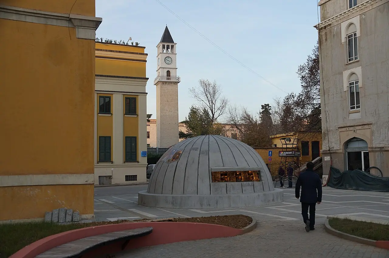 The concrete bunker dome entrance of Bunk'Art 2 next to the clock tower in Tirana