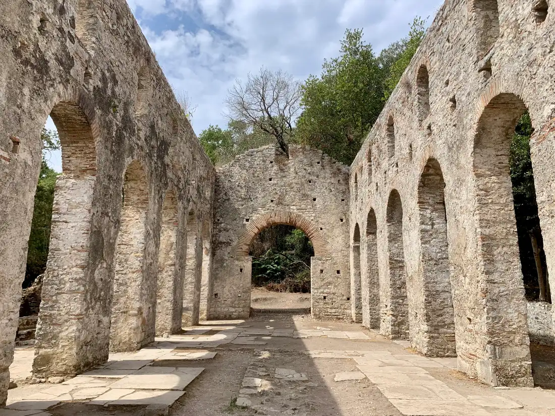 The roofless nave of the Great Basilica at Butrint, lined with tall stone arches on both sides