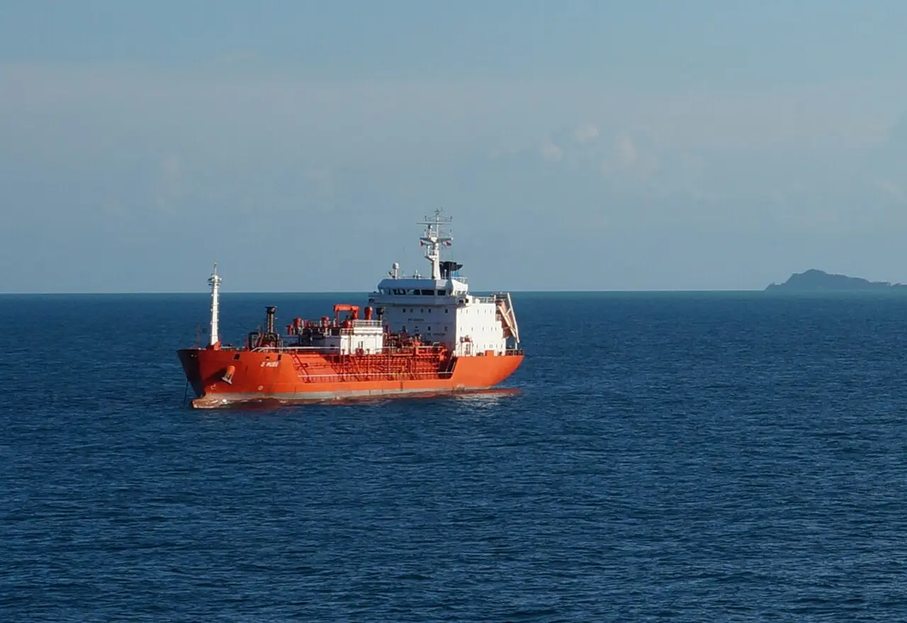 A cargo ship at anchor in Durrës bay with low hills behind the Adriatic harbour