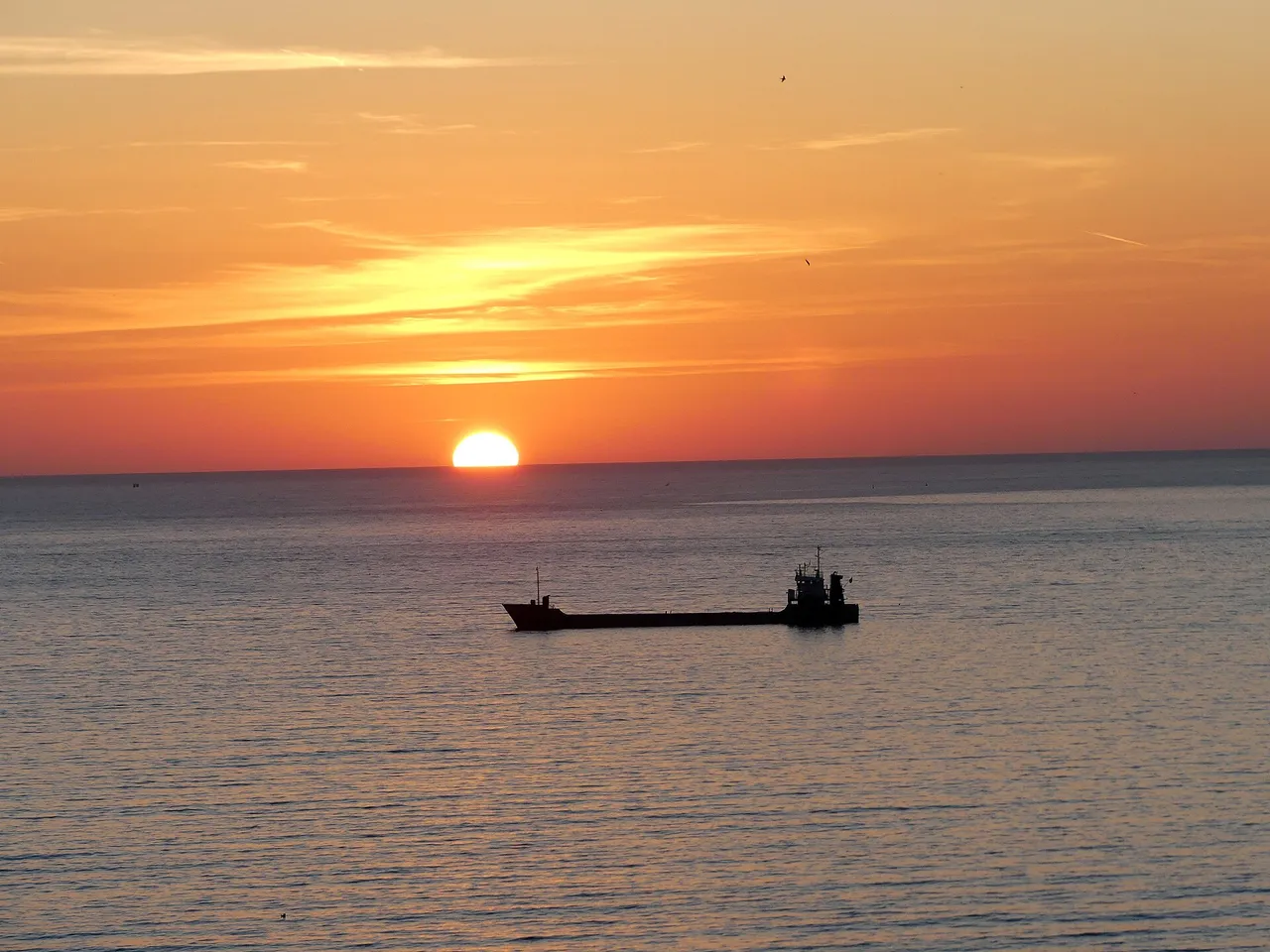 Sunset over Vlora bay with a ship silhouetted against the orange sky