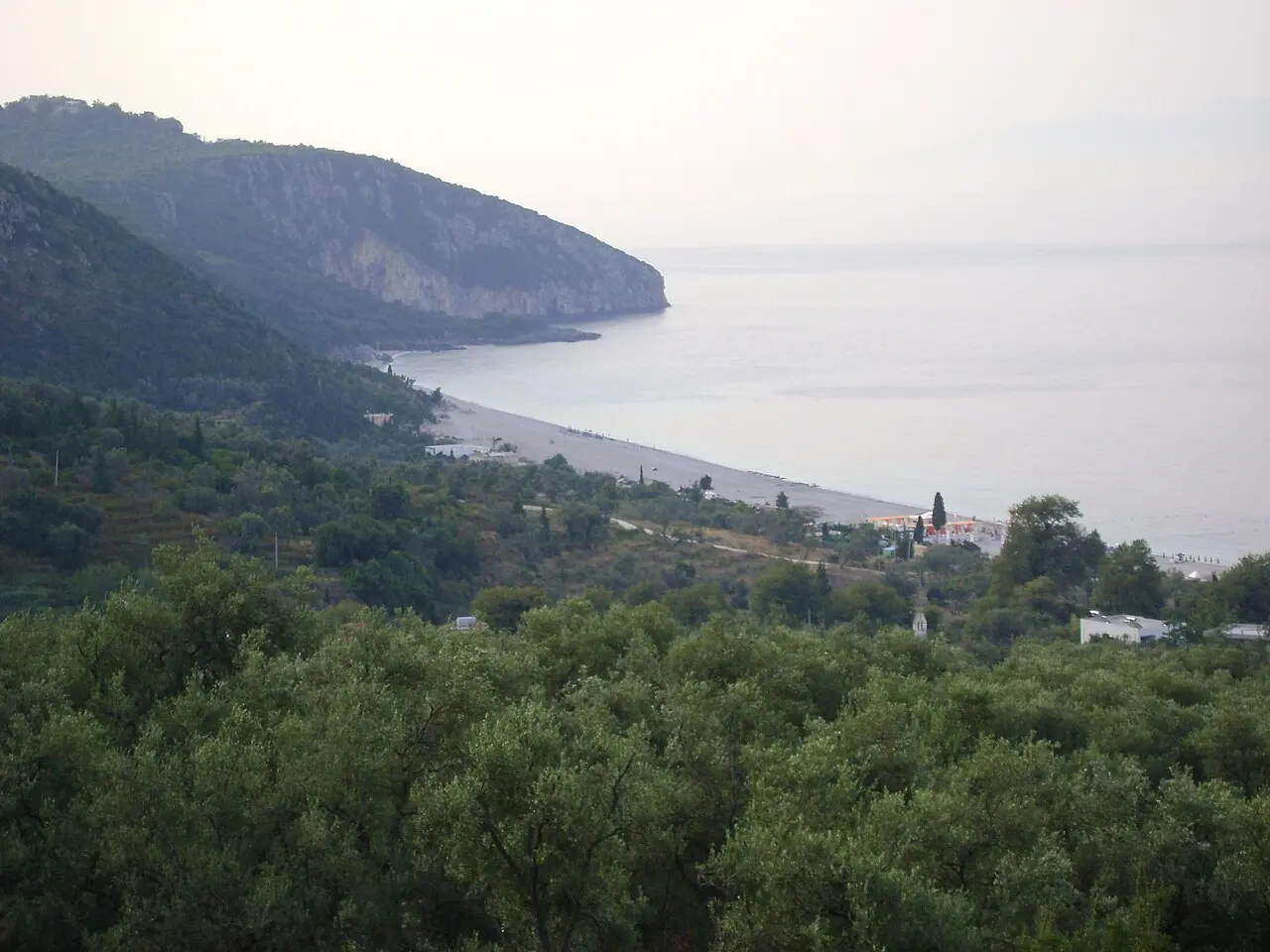 The long pebble beach at Dhermi with sunbeds, umbrellas and hills dropping to the sea