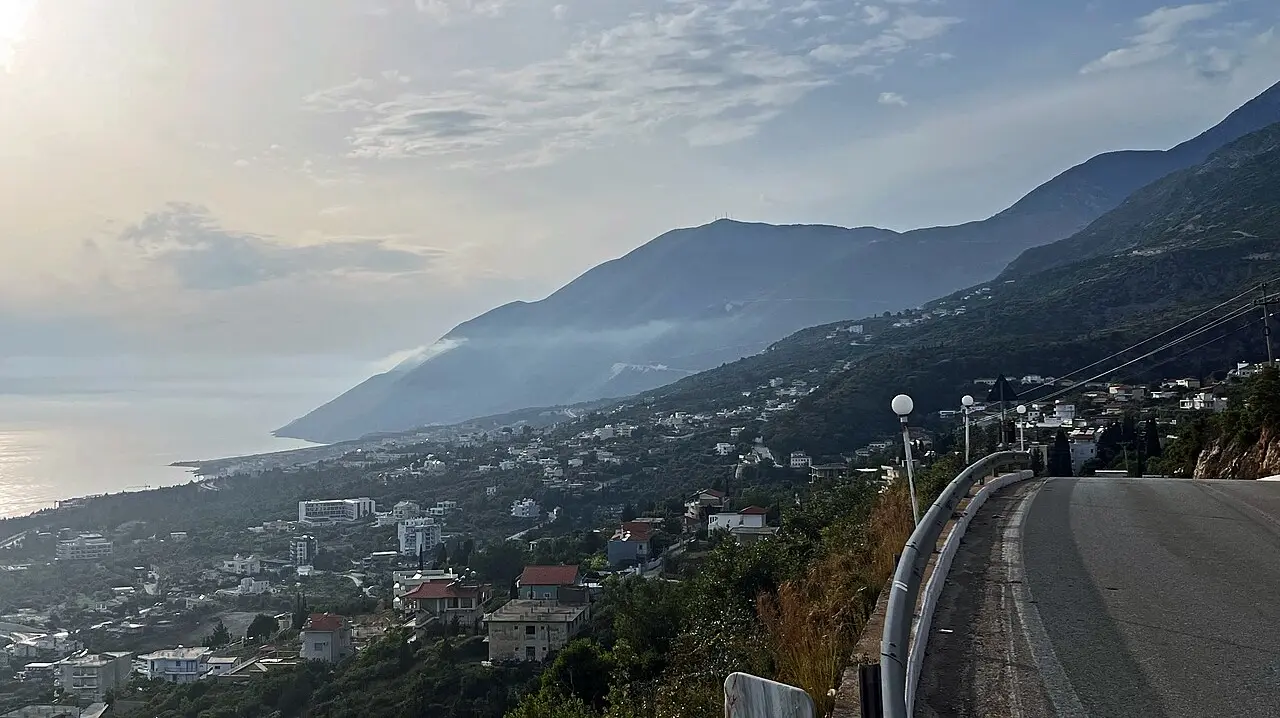 The coast at Dhermi with turquoise water below the steep green slopes of the Ceraunian Mountains