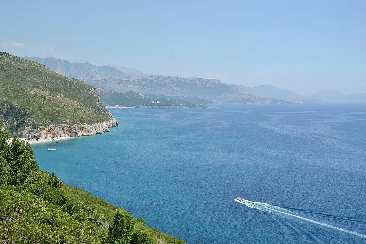 Gjipe beach at the mouth of its canyon, with pale pebbles, clear sea and steep rock walls