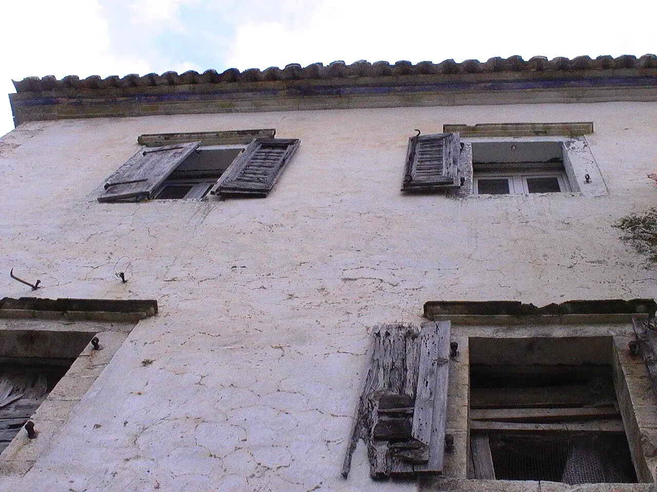 Shuttered windows and worn stonework on an old house in Dhermi village