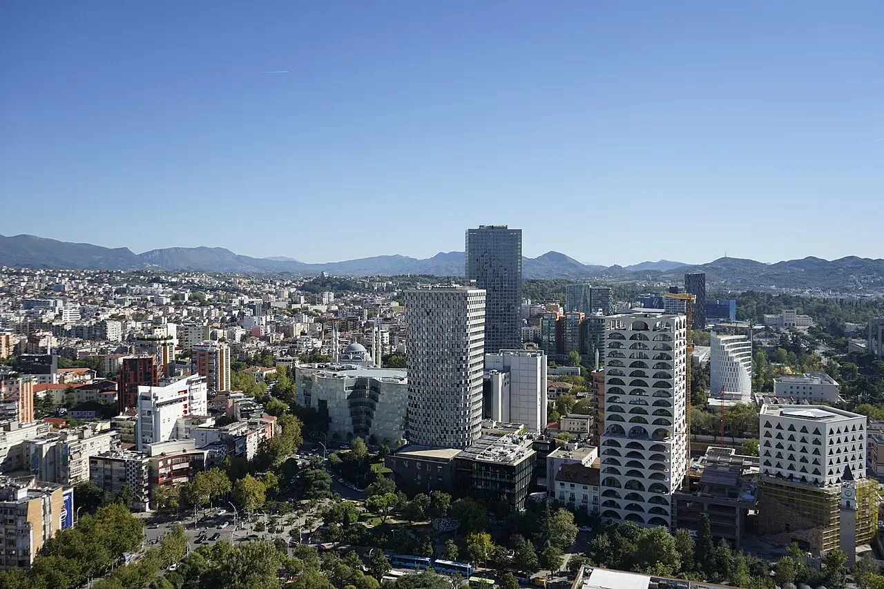 Aerial view over the modern Tirana skyline, with high-rise towers set against the surrounding mountains