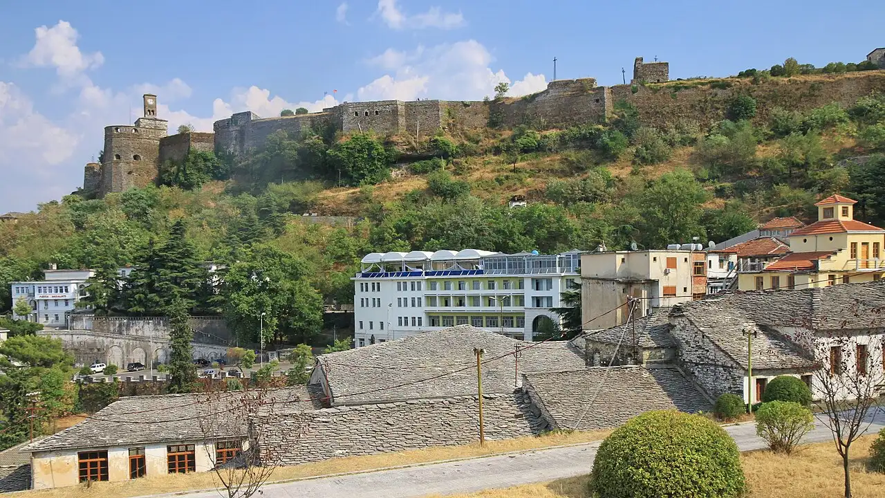 The grey stone fortress of Gjirokastër stretched along its ridge above the slate-roofed Ottoman houses of the stone city