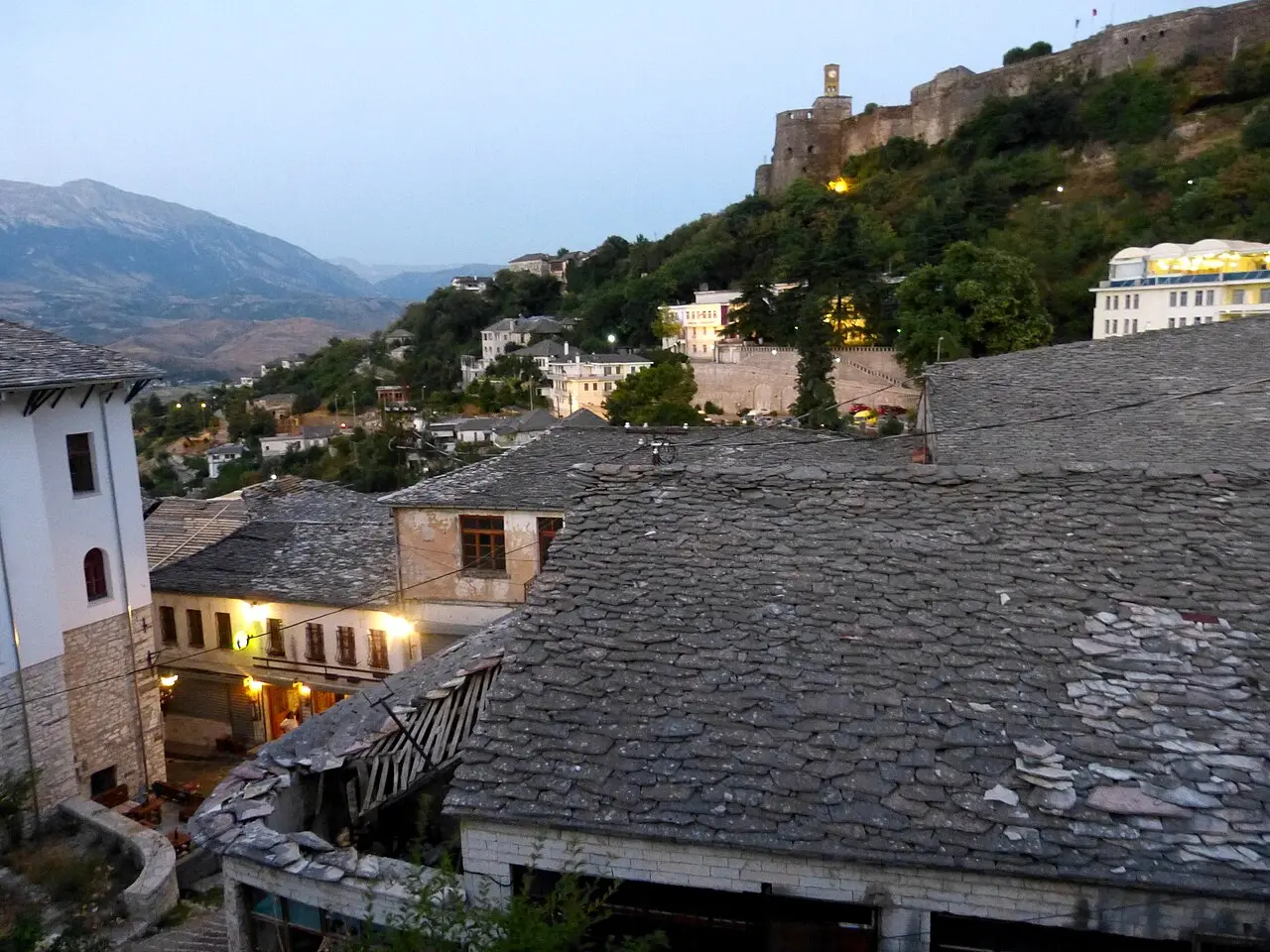 The slate roofs of Gjirokastër at dusk with the lit castle on the ridge above