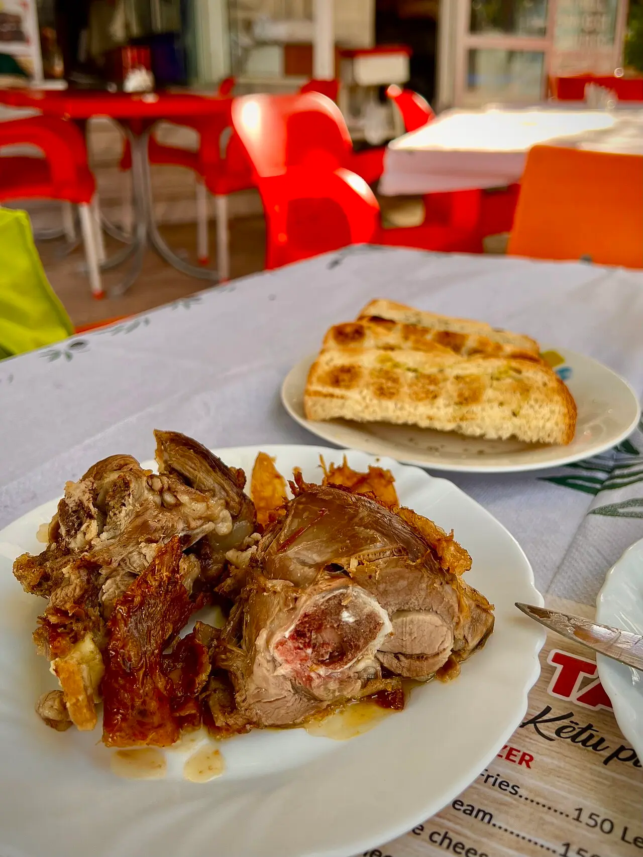 A plate of slow-cooked lamb with bread on a table at a Gjirokastër café