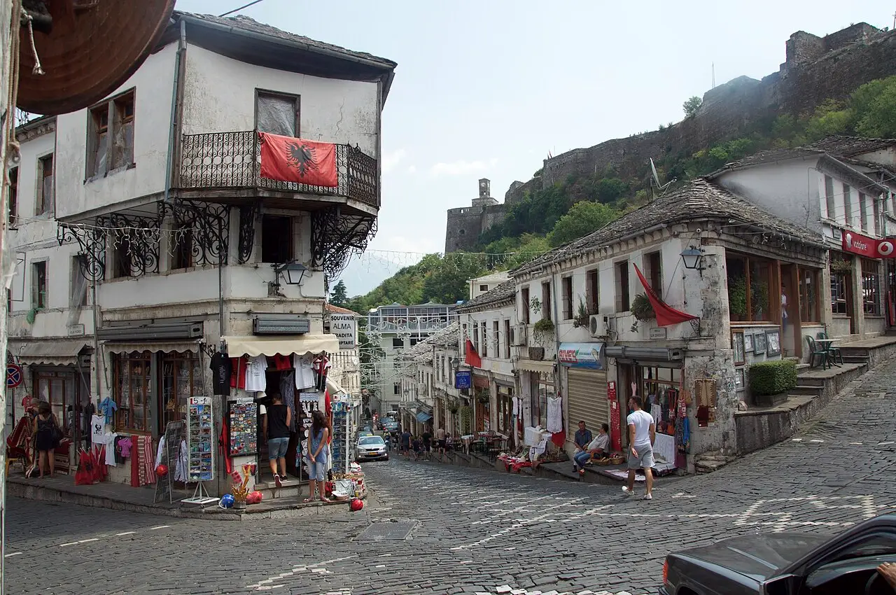 The cobbled junction of the Old Bazaar in Gjirokastër lined with stone shops, the castle wall above