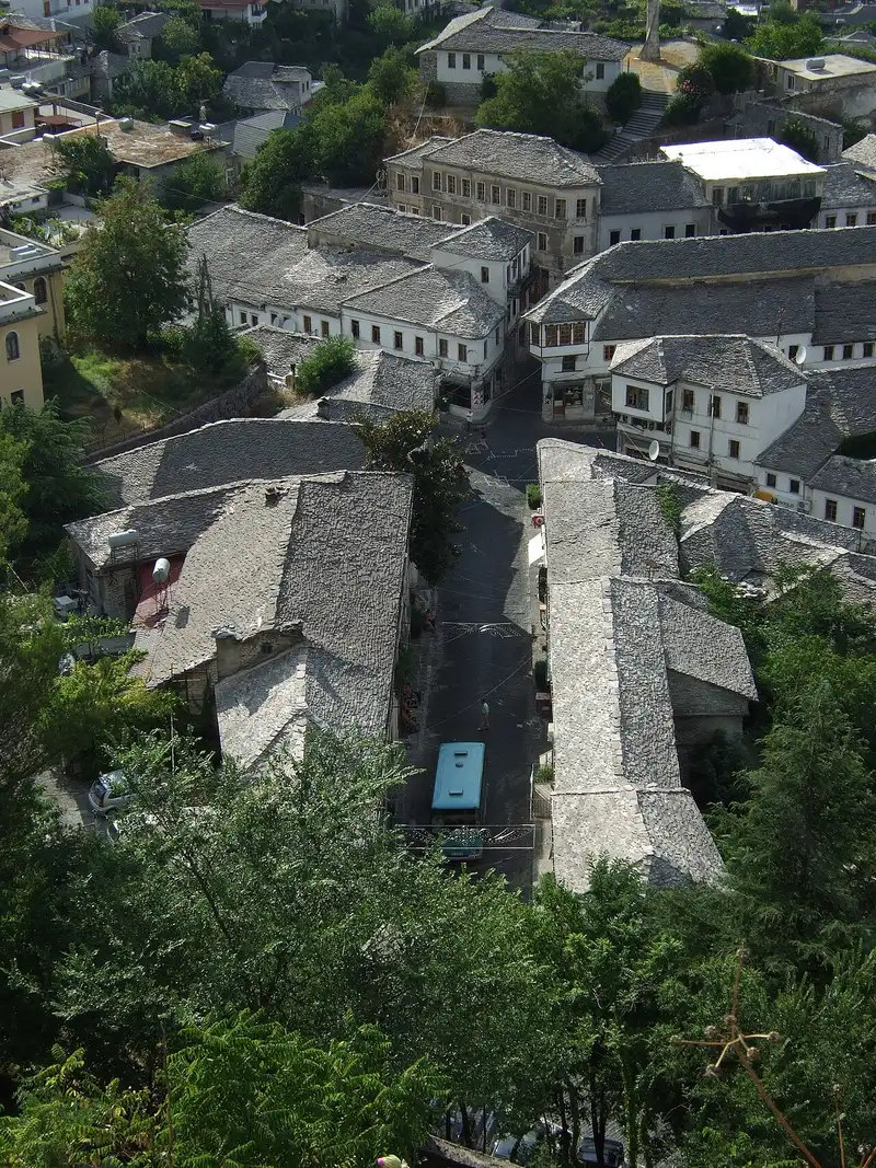 Aerial view over the grey stone-slab roofs of Gjirokastër clustered up the hillside