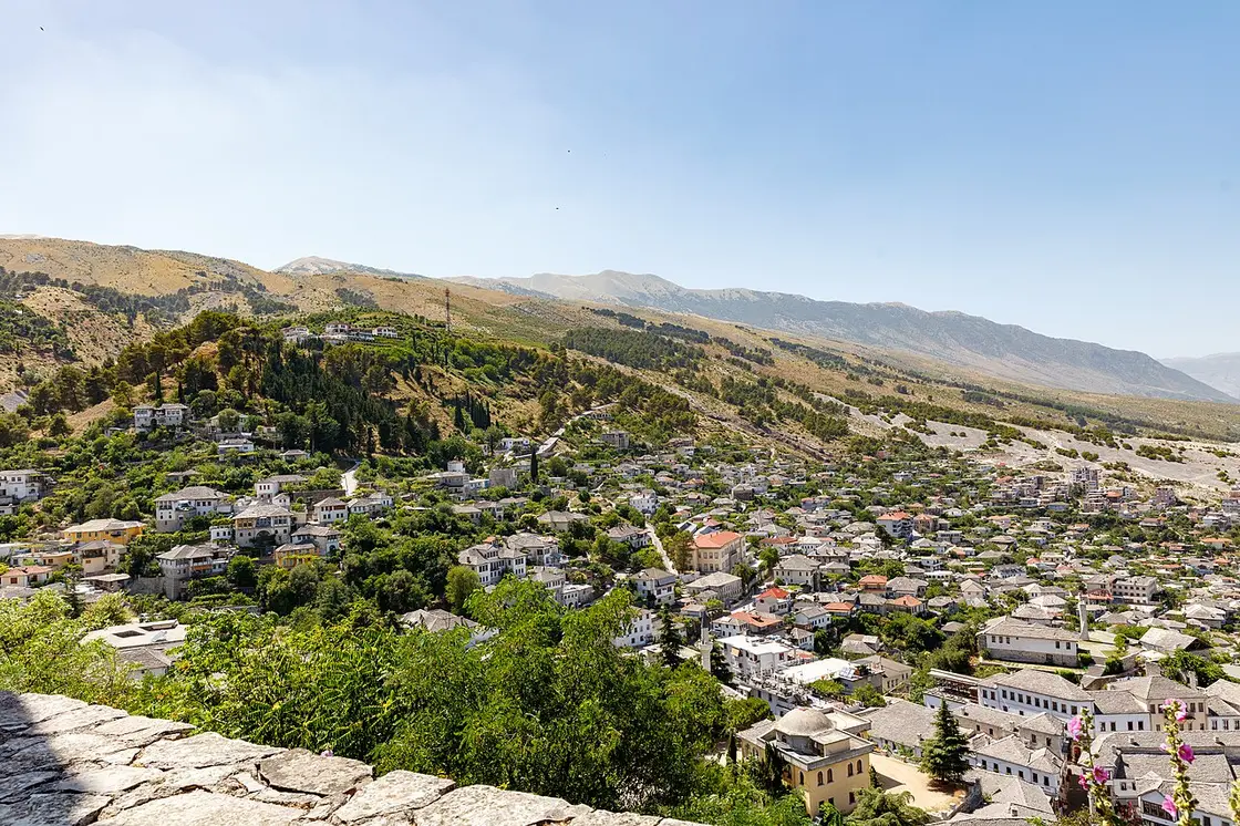 The houses of Gjirokastër climbing the green hillside below the castle ridge
